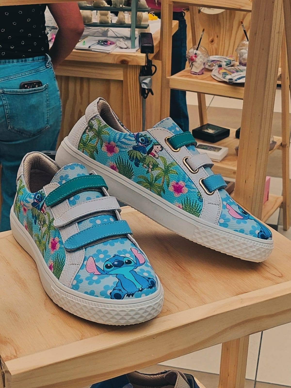 Par de sneakers de estampado tropical sobre una repisa, con la tienda al fondo