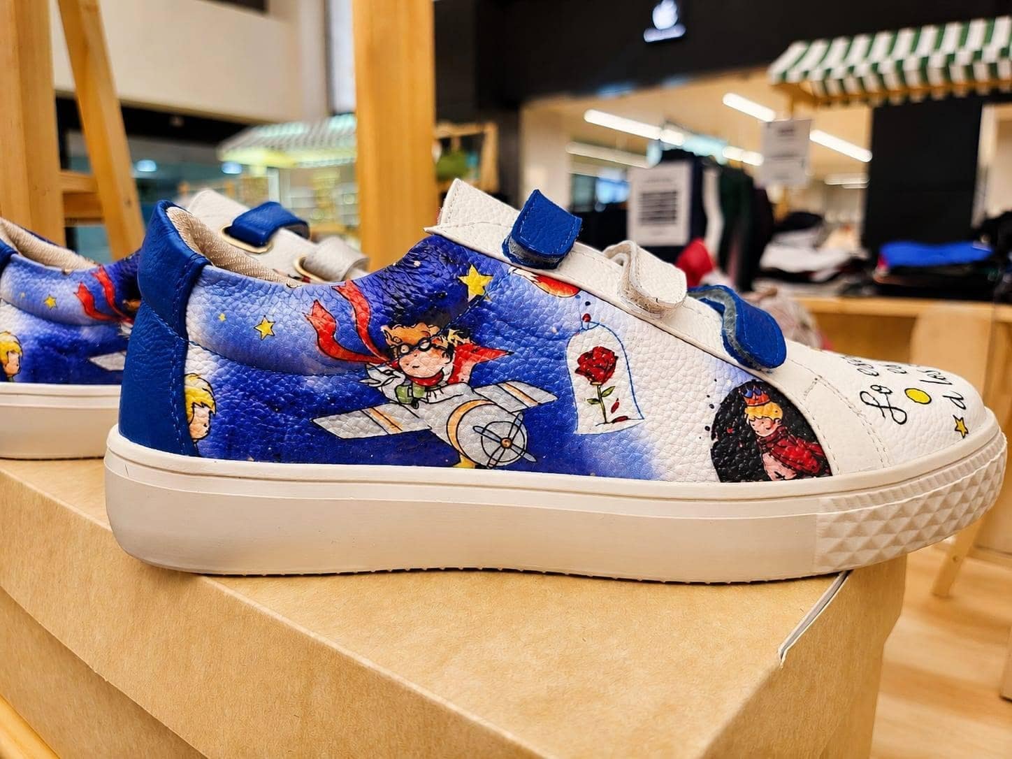 Detalle del panel azul del sneaker: un aviador en su avión, una rosa y estrellas ilustradas sobre el cuero