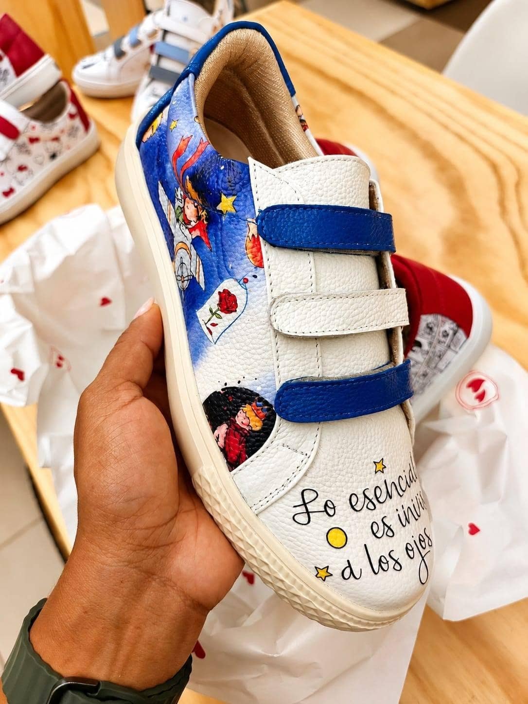 Sneaker sostenido en la mano, con la frase caligráfica visible en el costado